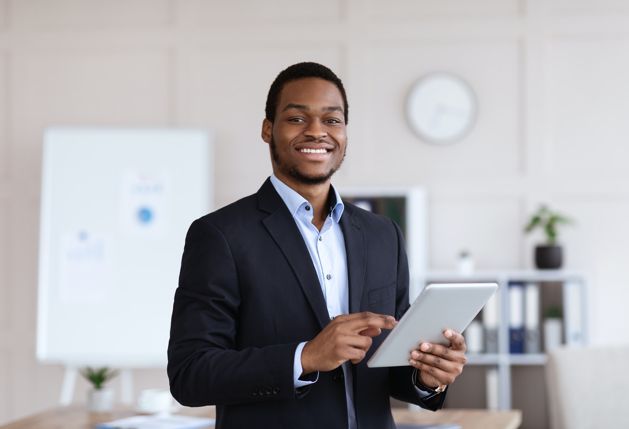 smiling-black-entrepreneur-holding-digital-tablet-office-interior.jpg